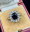 Antique ring with a dark bue sapphire gemstone and diamond accents on a velvet cushion