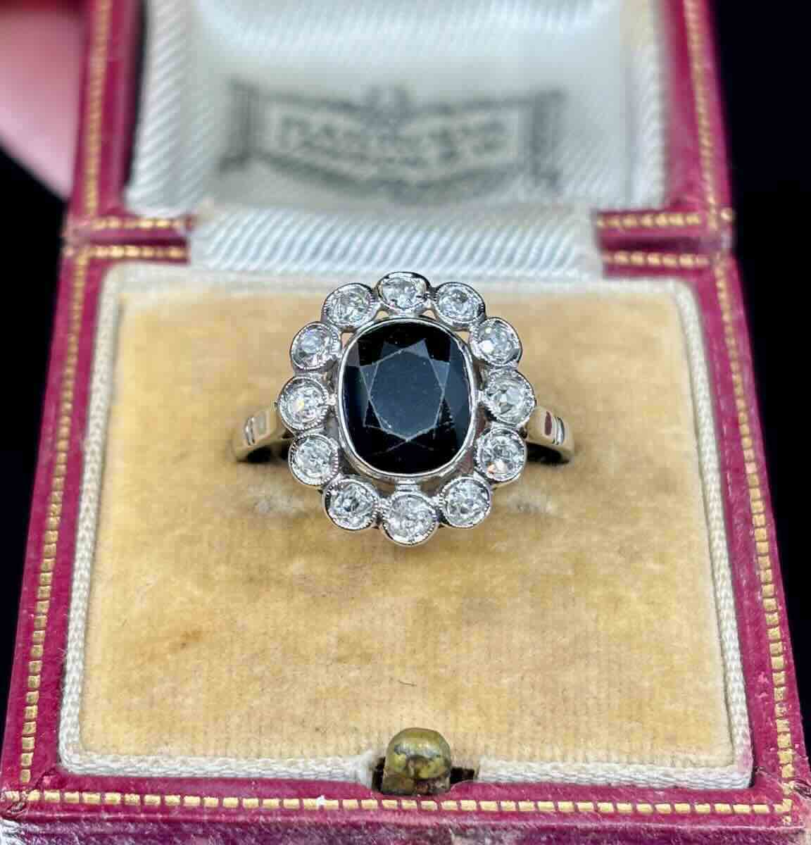Vintage ring with a central navy blue stone and diamond accents in a decorative box.
