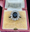 Vintage ring with a central navy blue stone and diamond accents in a decorative box.