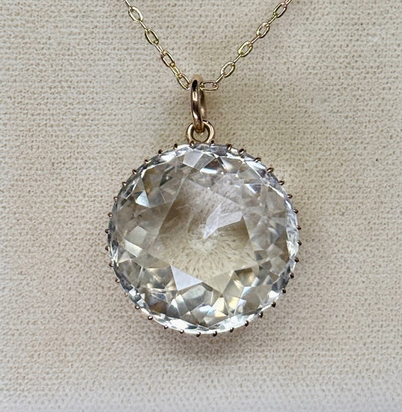 Front view of an antique Victorian rock crystal pendant with a high-domed faceted round crystal in 9ct yellow gold