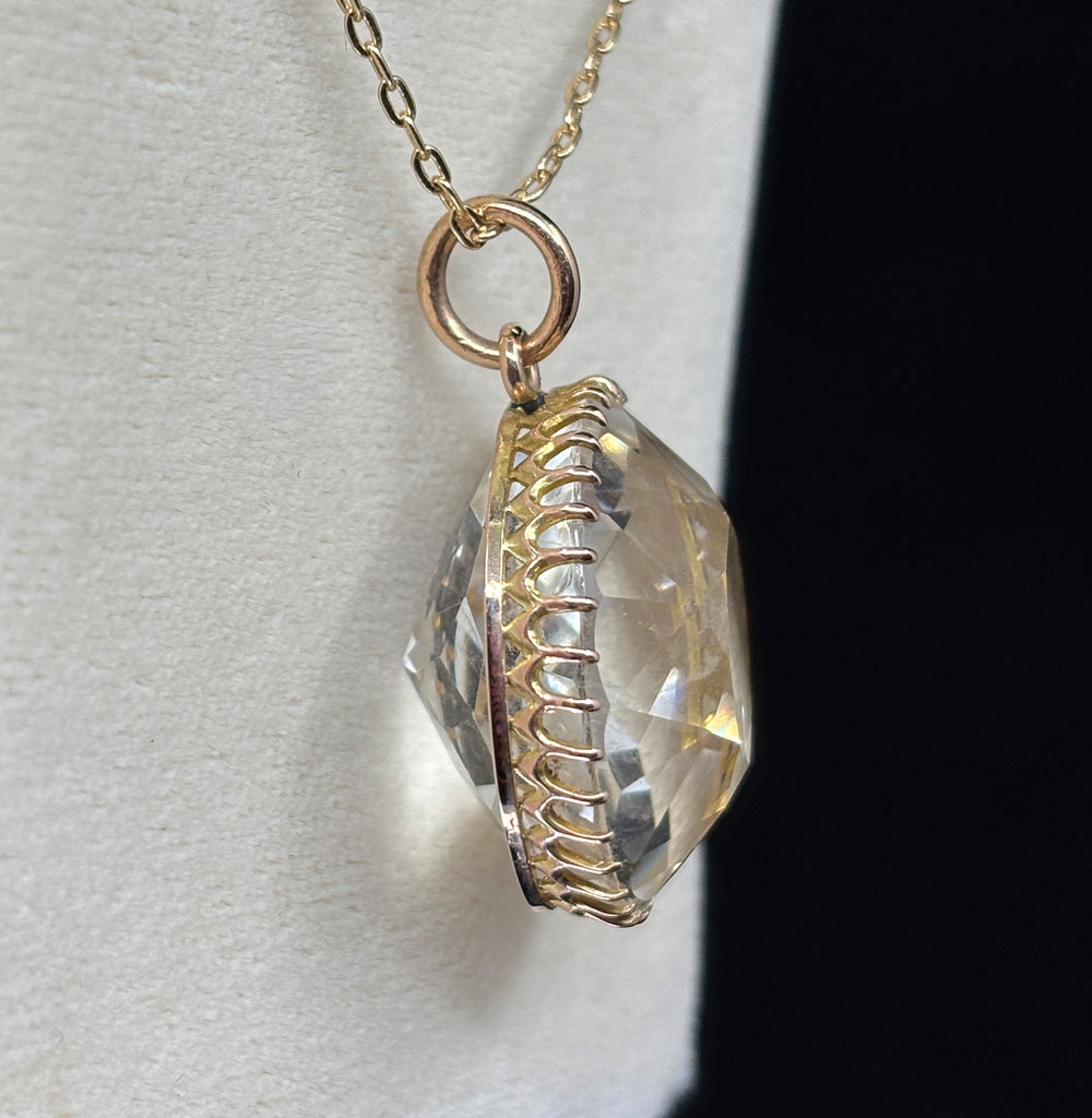 Side view of the antique Victorian rock crystal pendant highlighting the domed profile and scalloped 9ct gold gallery