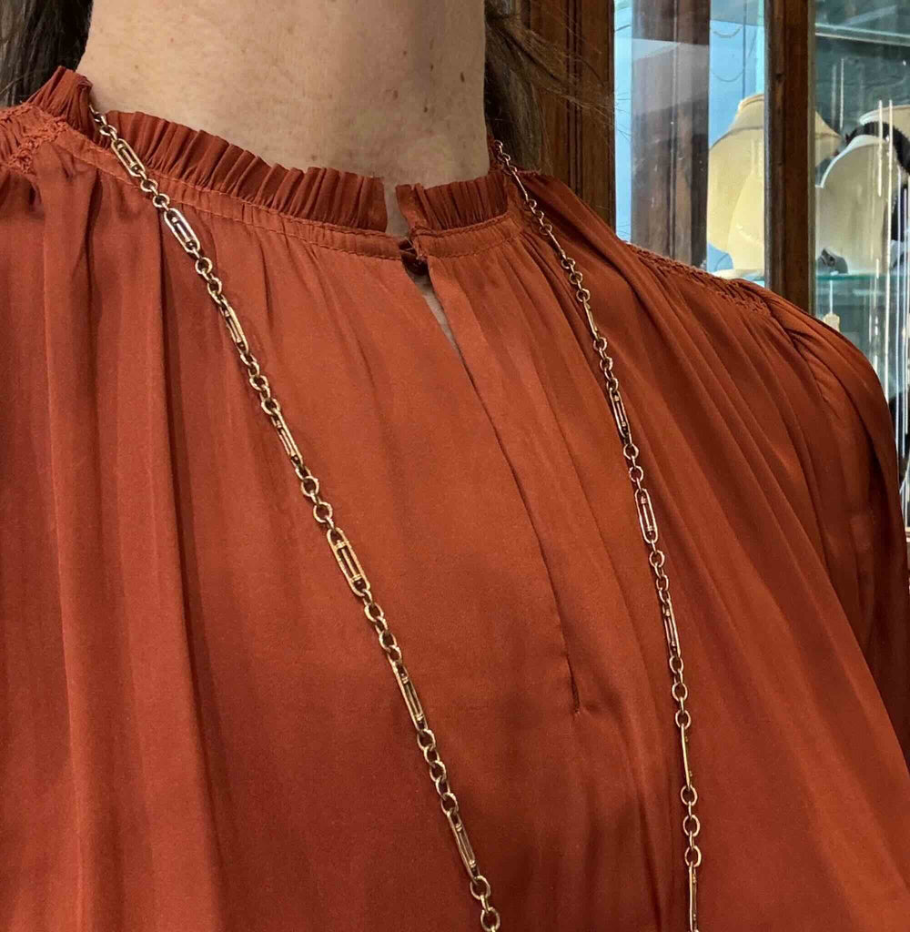 Antique Edwardian gold guard chain worn long over a blouse, showing the alternating fancy and round link pattern