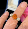 Spessartite garnet and old european cut diamond trilogy ring shown being worn on the finger.
