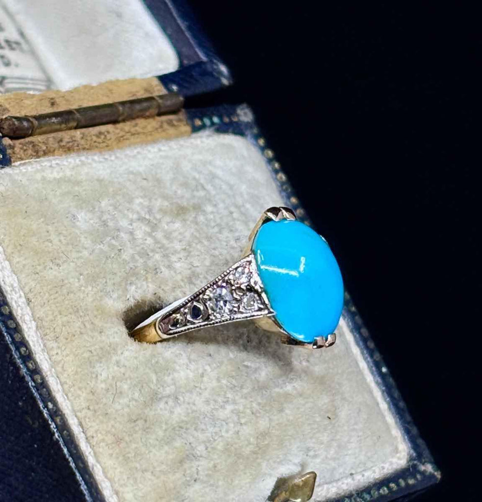 Close-up of a vintage 1920s turquoise ring, showcasing a vibrant oval turquoise stone set in intricately designed 18ct yellow gold.
