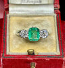 1930s emerald‑cut emerald and diamond three‑stone ring in platinum, untreated natural Colombian emerald.