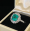 Antique_emerald_cut_emerald_and_diamond_cluster_ring