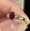 2.53ct oval ruby three‑stone ring worn on finger, warm 9ct yellow gold mounting and vintage sparkle from SI clarity old‑European diamonds.
