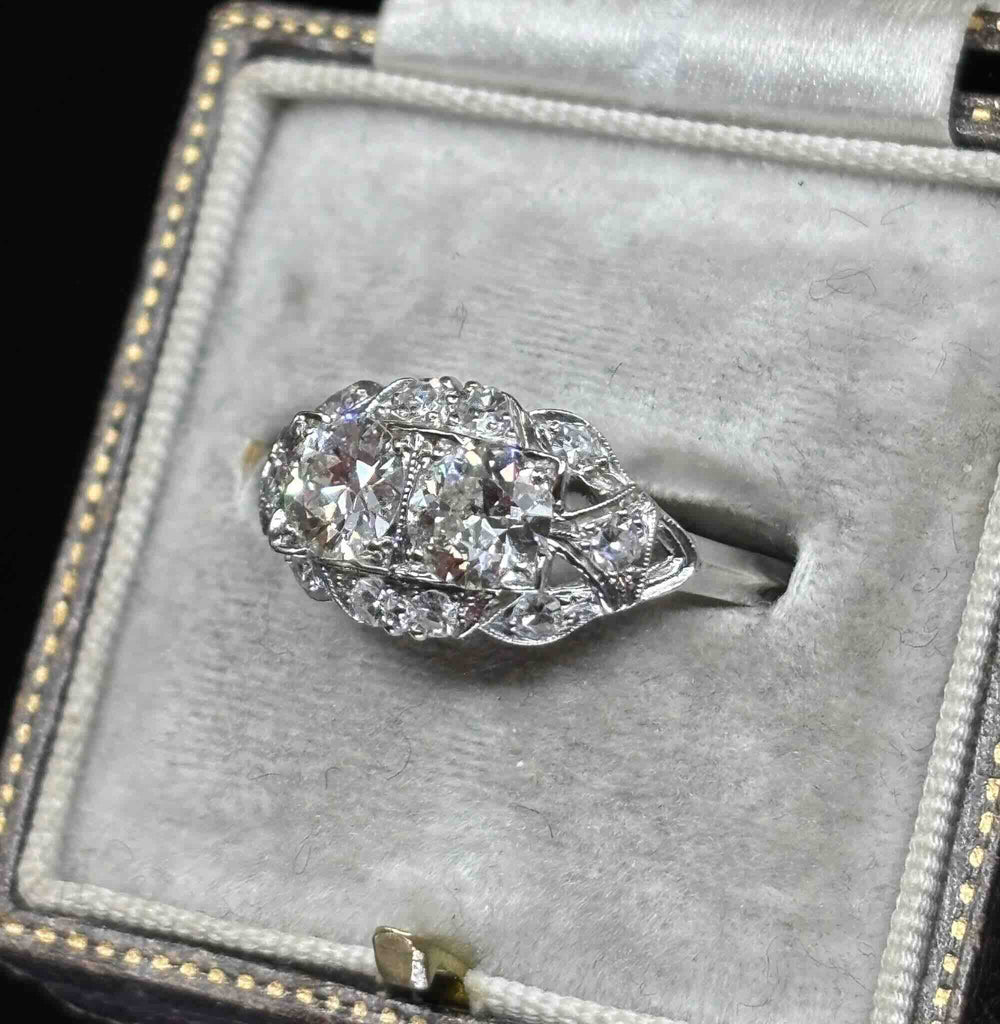 Angled view of the Art Deco diamond cluster ring showing toi et moi diamonds, milgrain borders and a pierced platinum gallery