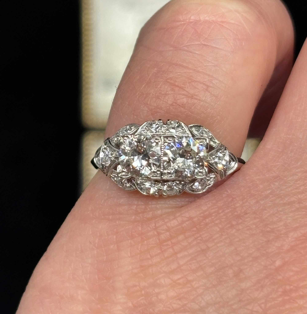 Art Deco diamond cluster ring worn on the hand, showing twin Old European cut diamonds surrounded by ten single-cut diamonds