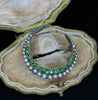 Angled view of the Victorian crescent moon brooch with graduated demantoid garnets and natural pearls in its antique case