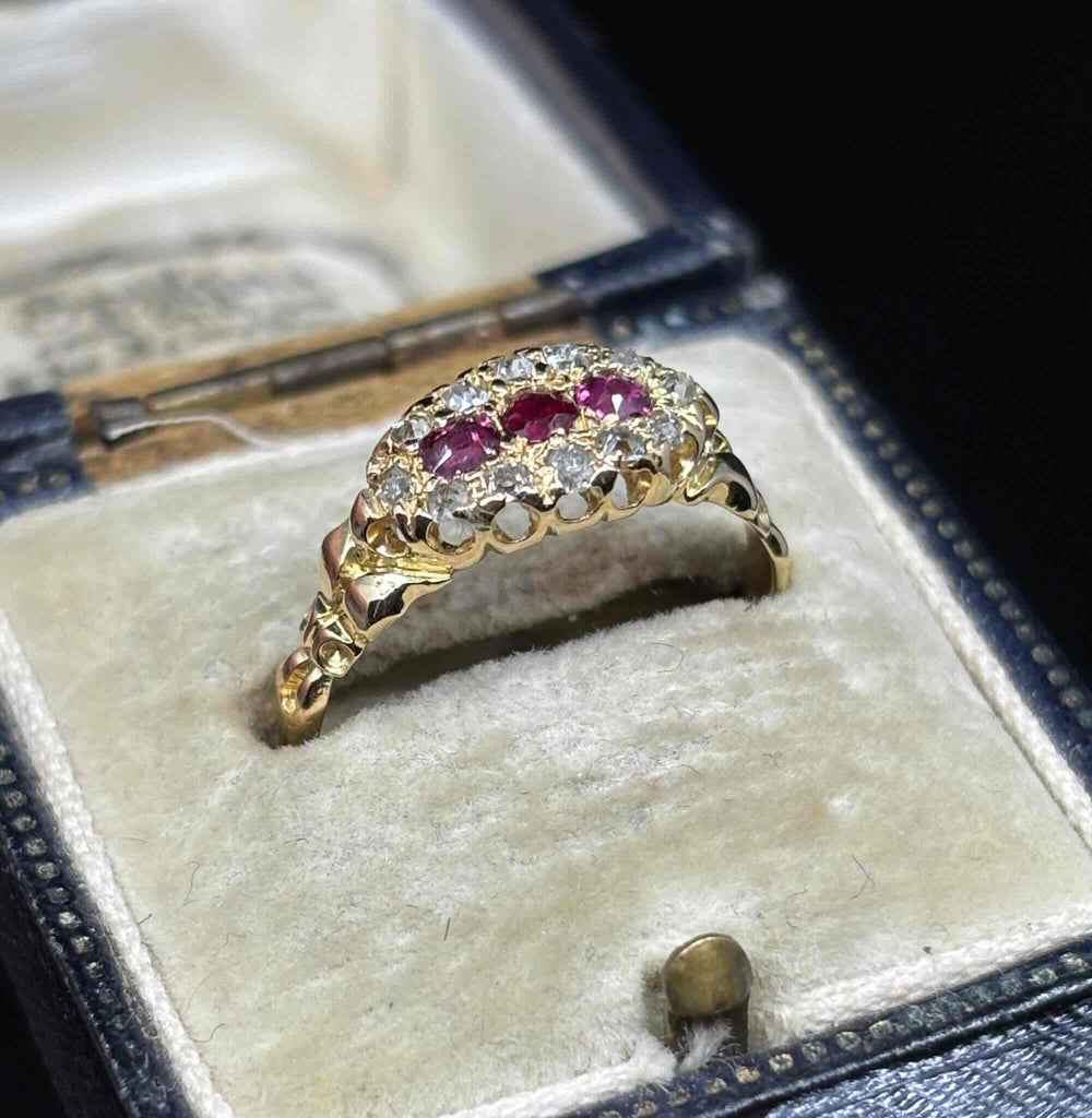 Angled view of the Edwardian ruby and diamond cluster ring showing the elevated setting and carved yellow gold shoulders
