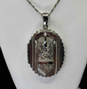 Front view of an antique Victorian sterling silver buckle locket with hand-engraved foliate scrollwork and scalloped border
