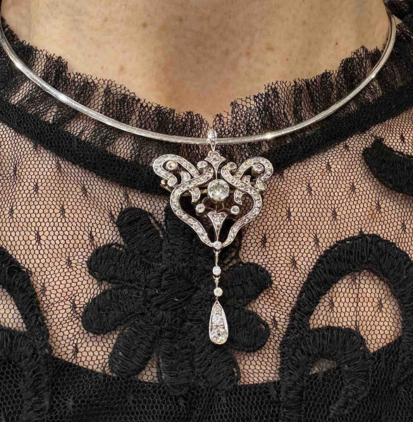 Antique Victorian diamond pendant brooch worn on a collar necklace, showing its openwork scroll design and five-stone drop