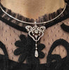 Antique Victorian diamond pendant brooch worn on a collar necklace, showing its openwork scroll design and five-stone drop