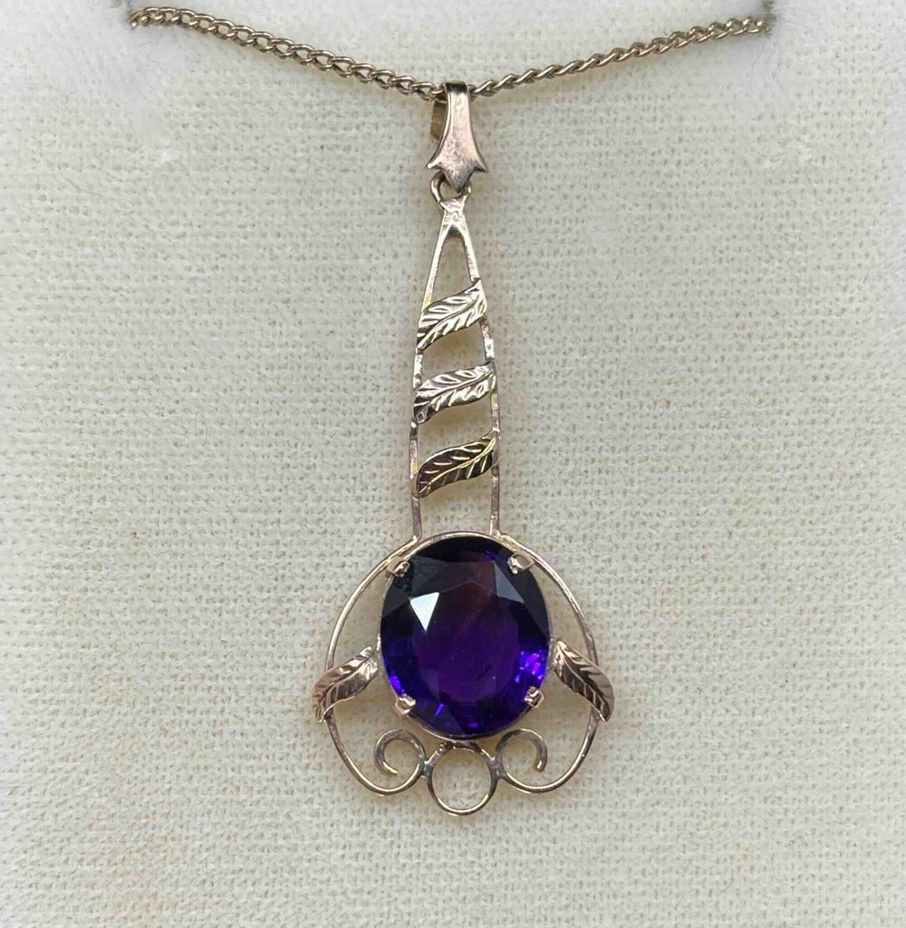 front on view of the oval purple amethyst surrounded by a delicate handmade rose gold frame against a cream background