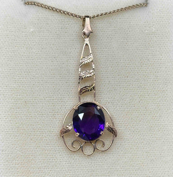 front on view of the oval purple amethyst surrounded by a delicate handmade rose gold frame against a cream background