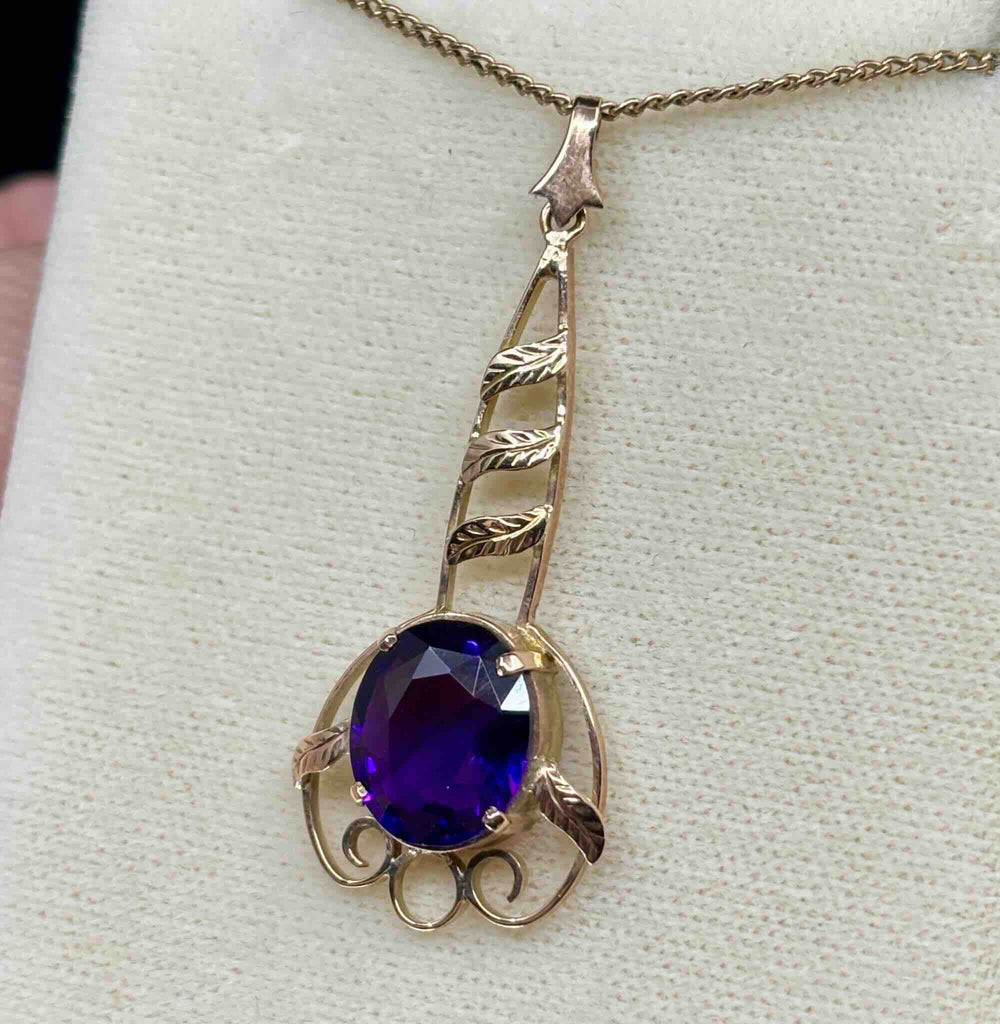 Side view of the antique amethyst pendant showcasing the size of the oval stone and the dark, deep, transparent purple colour of the amethyst. 