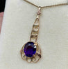 Side view of the antique amethyst pendant showcasing the size of the oval stone and the dark, deep, transparent purple colour of the amethyst. 