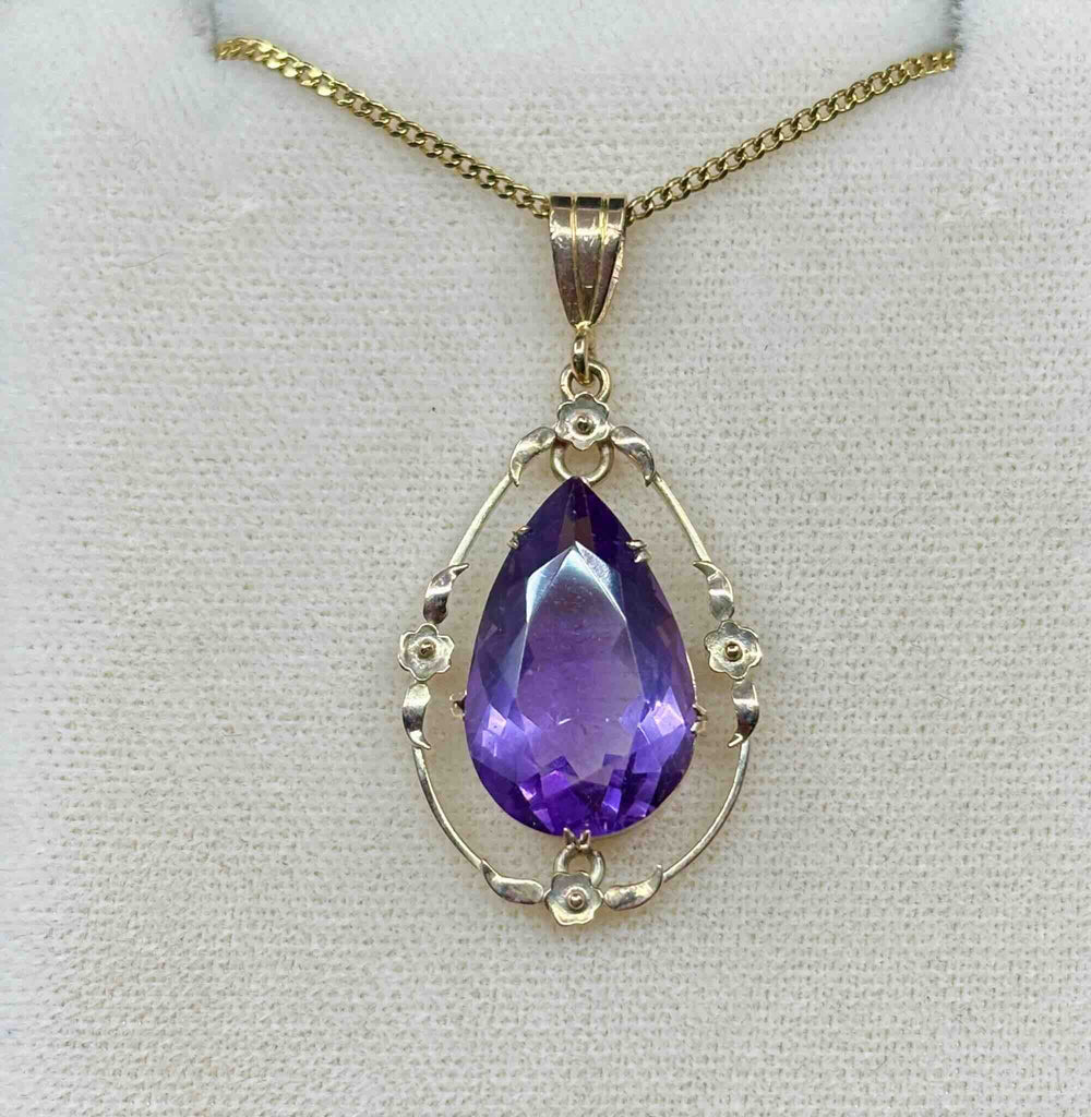 antique Australian pendant with a central pear shaped purple amethyst and a simple, delicate 9ct yellow gold floral frame.