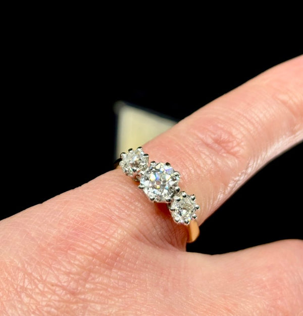 Antique diamond ring showcasing a reverse tapered band and three old cut diamonds.