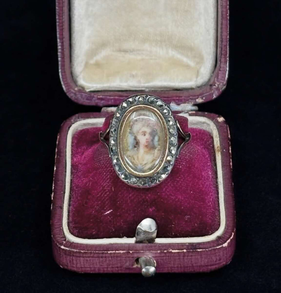 Exquisite Georgian portrait ring from 1810 featuring a painted portrait of an upper-class woman, surrounded by marcasite stones.
