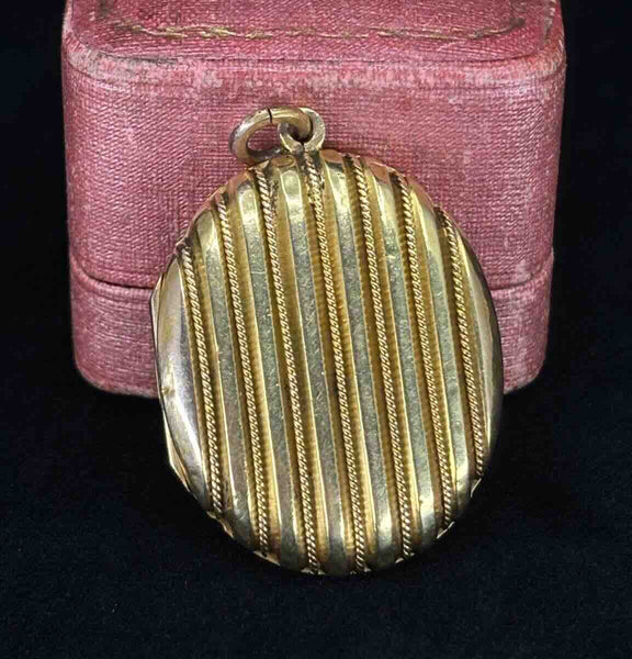 Antique Victorian 15ct yellow gold oval locket with striped design on a pink antique box.