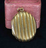 Antique Victorian 15ct yellow gold oval locket with striped design on a pink antique box.