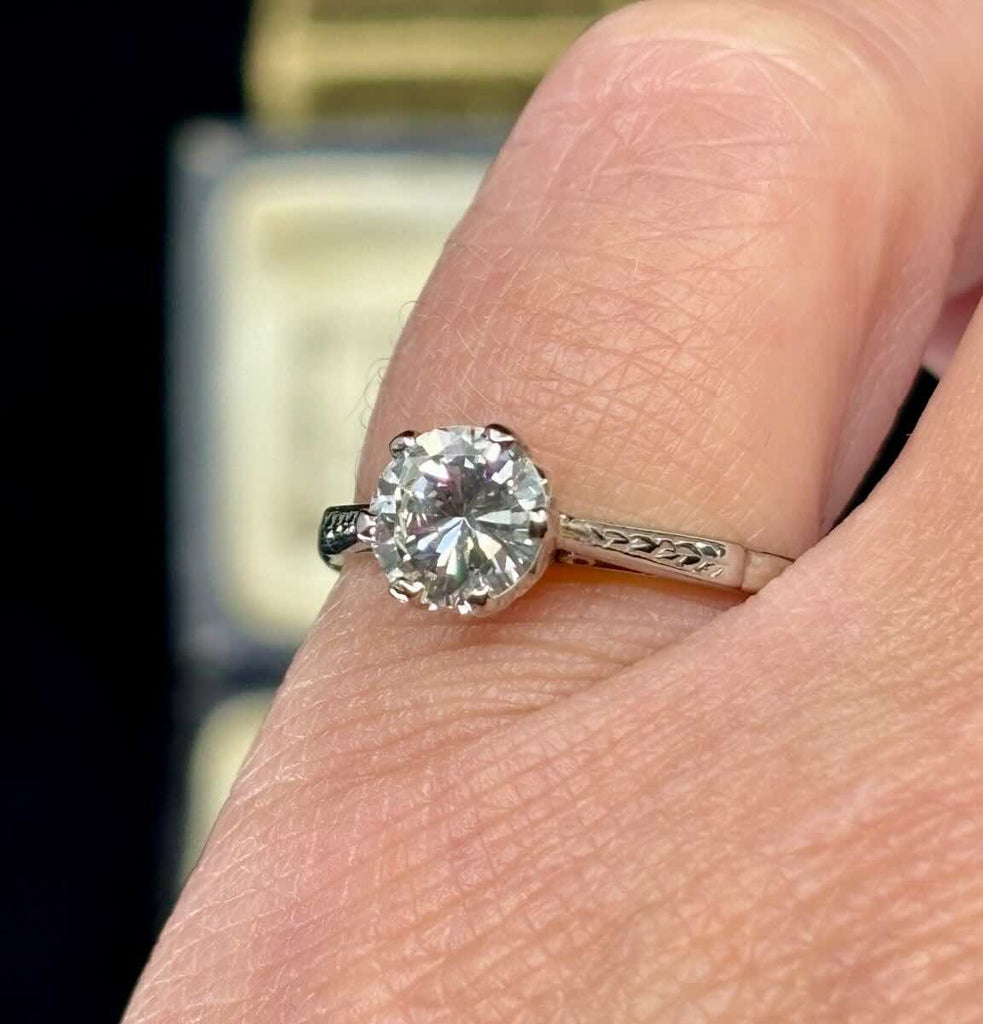 A classic 1950s six claw diamond ring set in platinum on the finger with intricate hand engraving