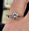 Platinum and diamond solitaire engagement ring on finger showing off the hand engraved feathering