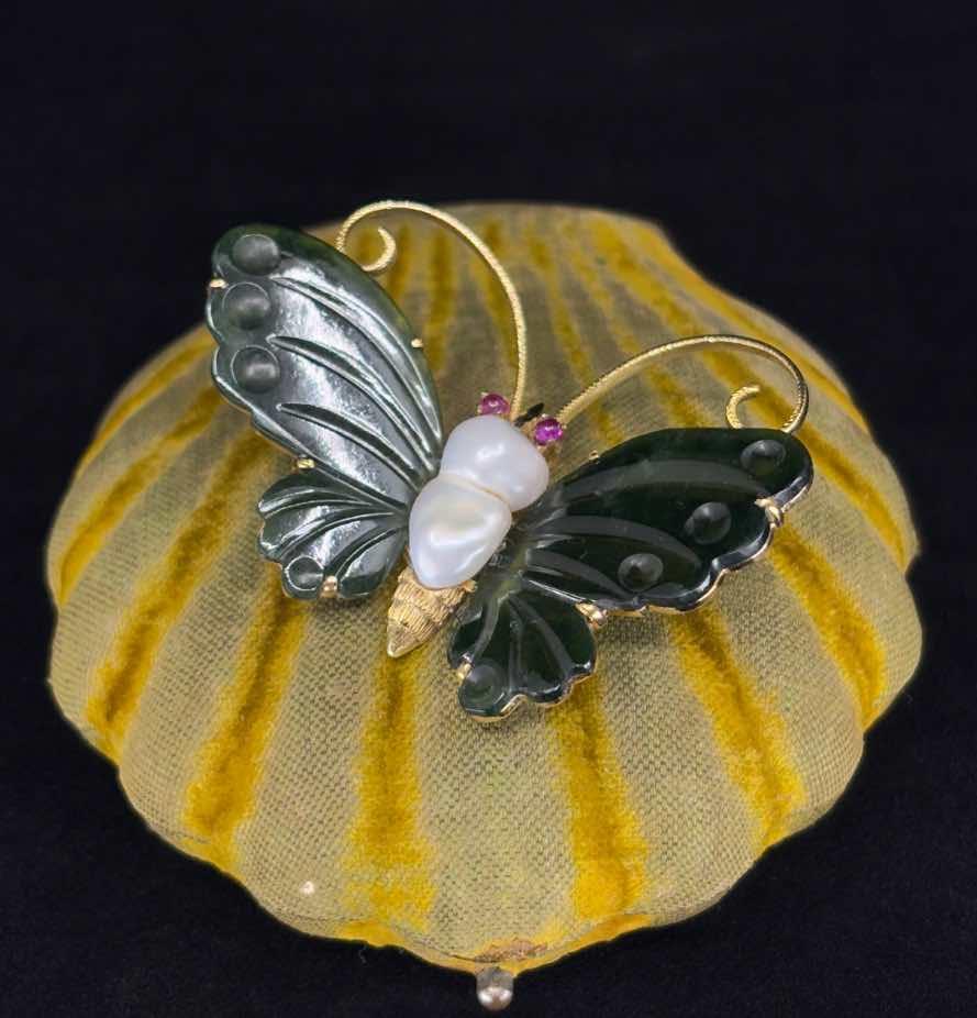 Detailed view of a gemstone butterfly brooch with intricately carved nephrite wings and cabochon cut ruby eyes.