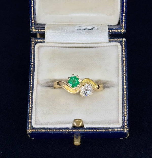 An antique-style engagement ring with a romantic 'Toi et Moi' design, featuring an emerald and diamond in 18ct yellow gold.