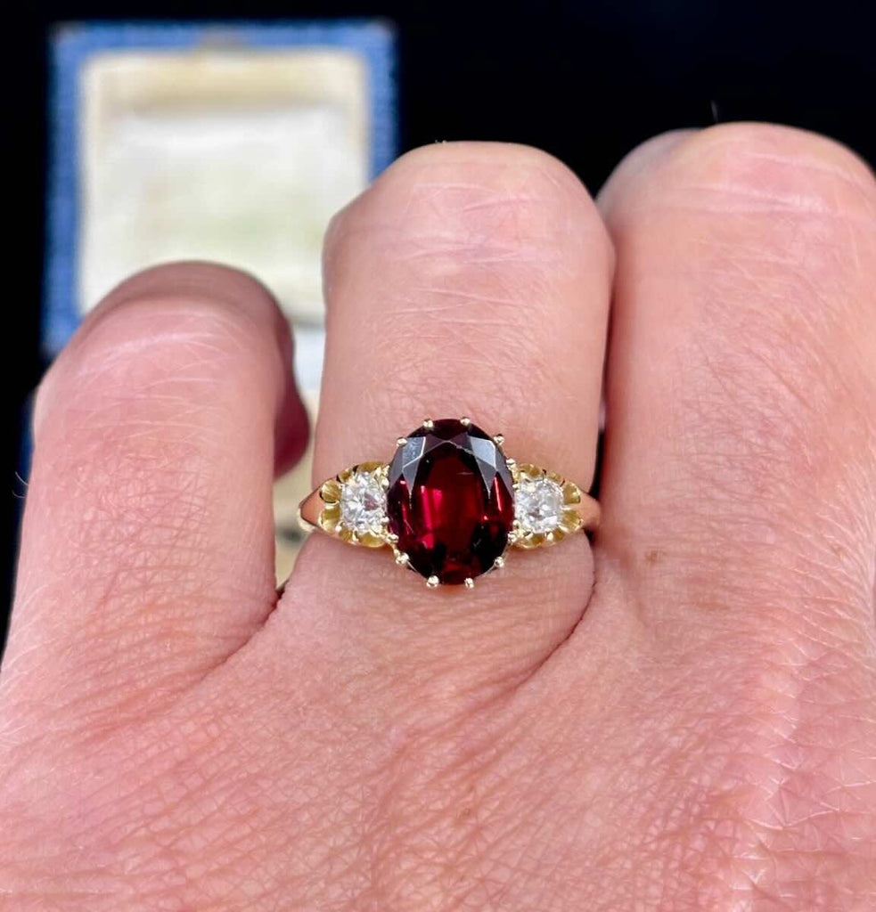 The Victorian almandine garnet and diamond three stone ring worn on the finger.