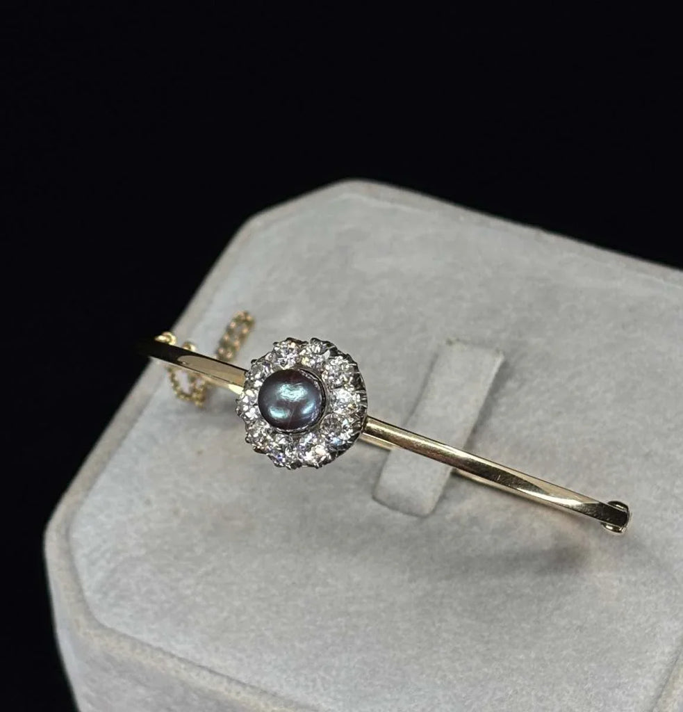 A Victorian 1880 natural black pearl and diamond flower cluster bangle on  side angle showing the pearls beautiful natural lustre.