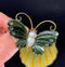 Close-up of a vintage butterfly brooch featuring a large baroque freshwater pearl, nephrite wings, and ruby eyes set in 14ct yellow gold.