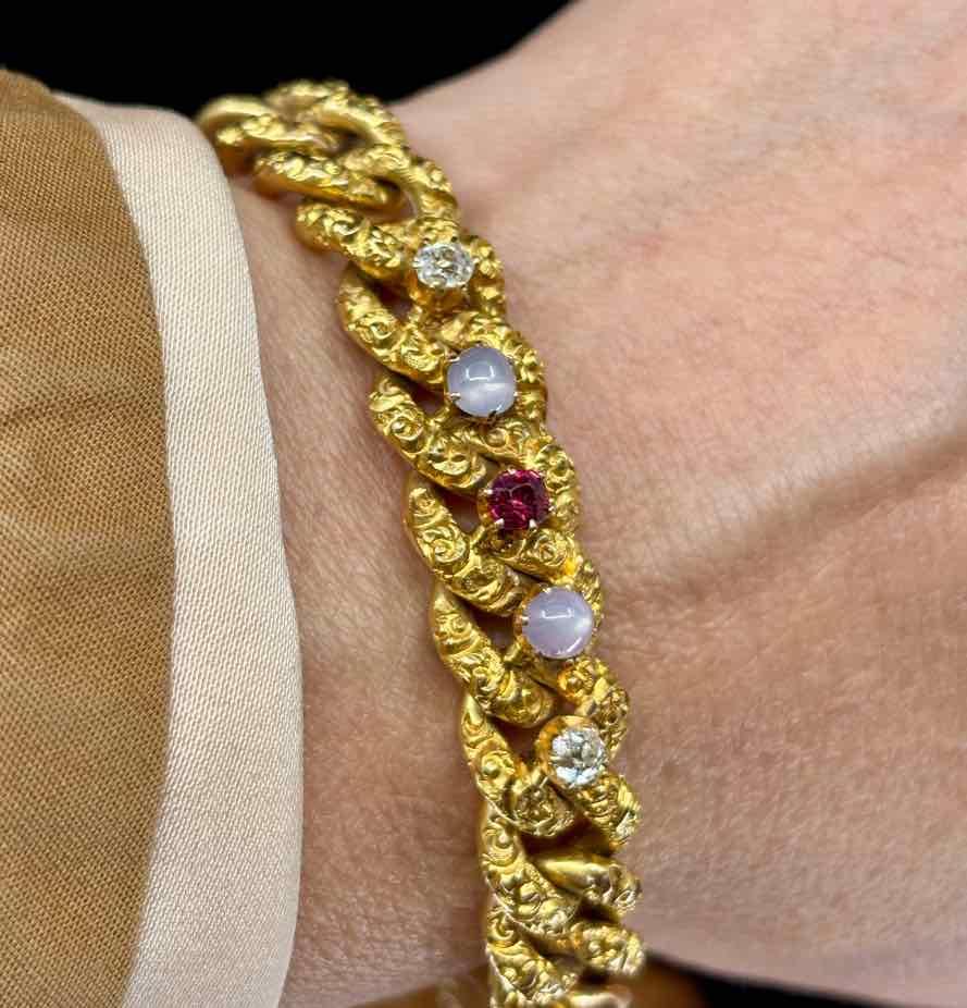 Vintage gold curb link bracelet adorned with ruby, diamond, and star sapphire accents.