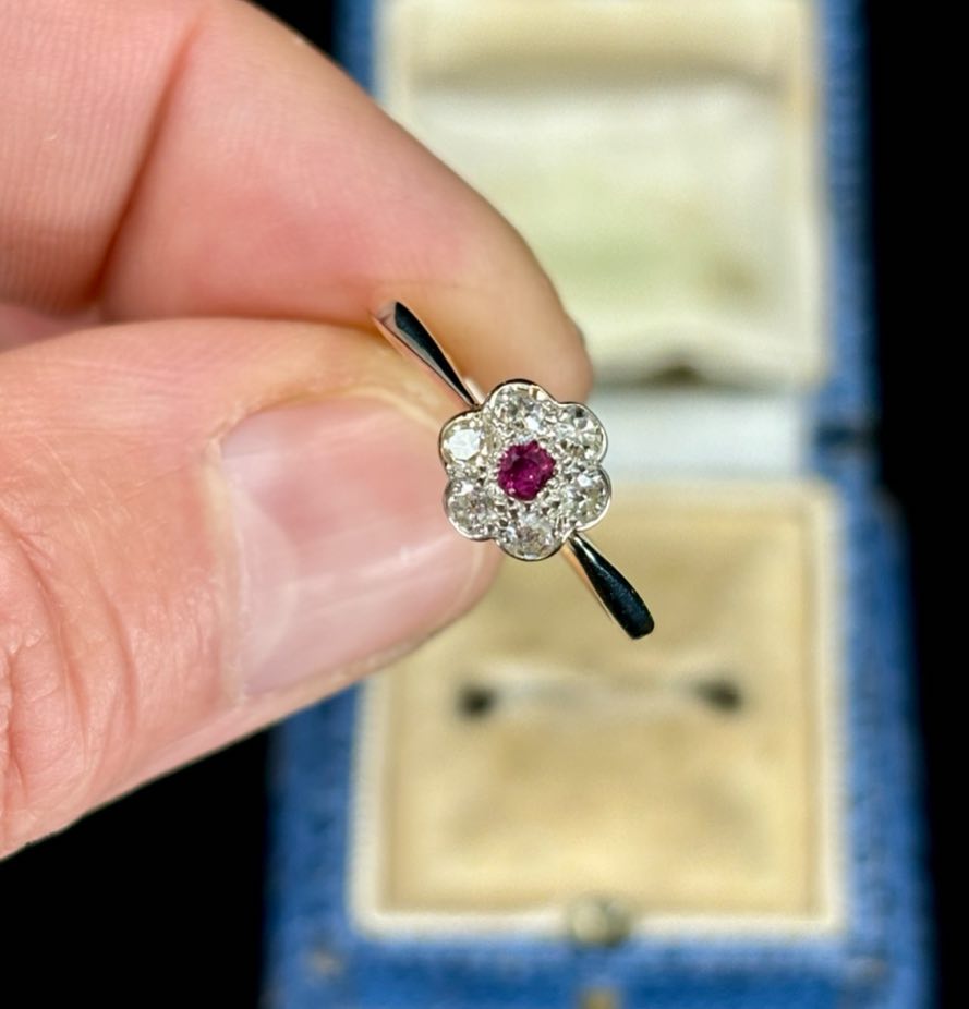 A captivating image of a 1920s Art Deco ring, showcasing the classic posy cluster style with a ruby centrepiece and diamond accents.