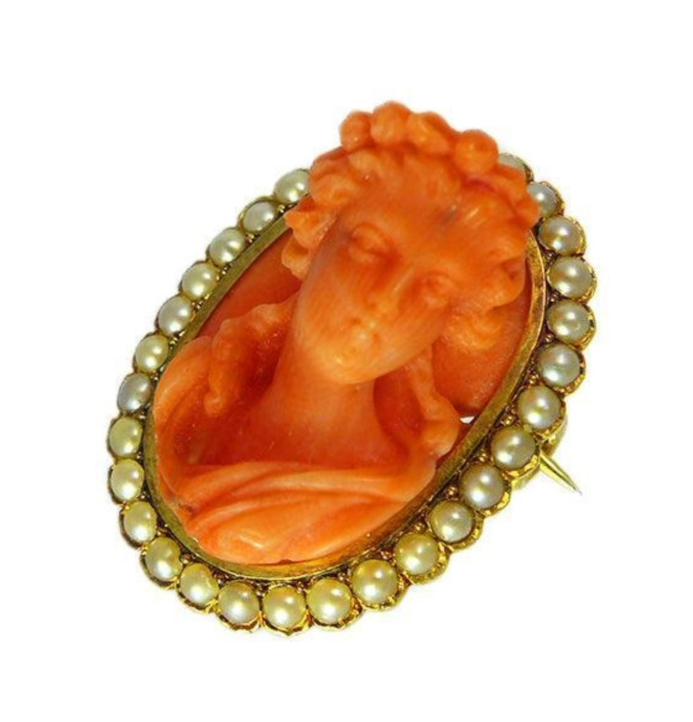 Angled view of Victorian coral and natural pearl cameo brooch highlighting fine carving, tool marks and warm patina.