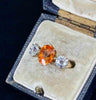 Three-stone ring from 1915, showcasing a stunning, rare bright orange spessartite garnet and two sparkling old european cut diamonds.