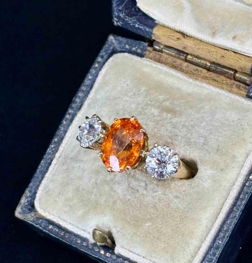 Three-stone ring from 1915, showcasing a stunning, rare bright orange spessartite garnet and two sparkling old european cut diamonds.
