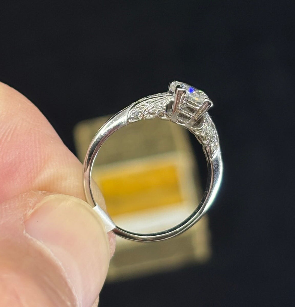 Antique 1920s platinum diamond ring showing detailed carved shoulders with 12 pavé single‑cut diamonds.