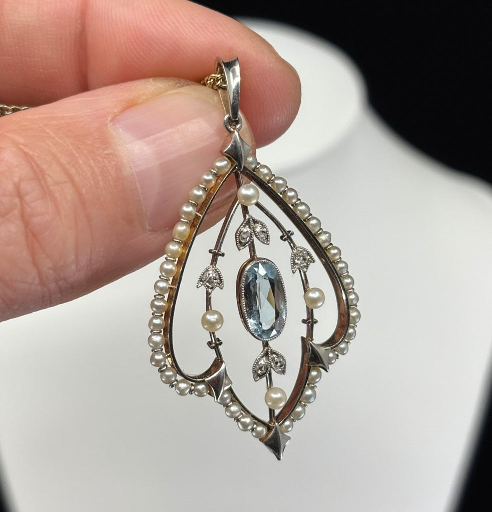 Antique Edwardian aquamarine and pearl pendant set in platinum and 15ct yellow gold, detailed foliate design and delicate pearl border.