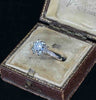 Antique diamond ring featuring a central old mine cut diamond and round brilliant cut diamonds on the shoulders.