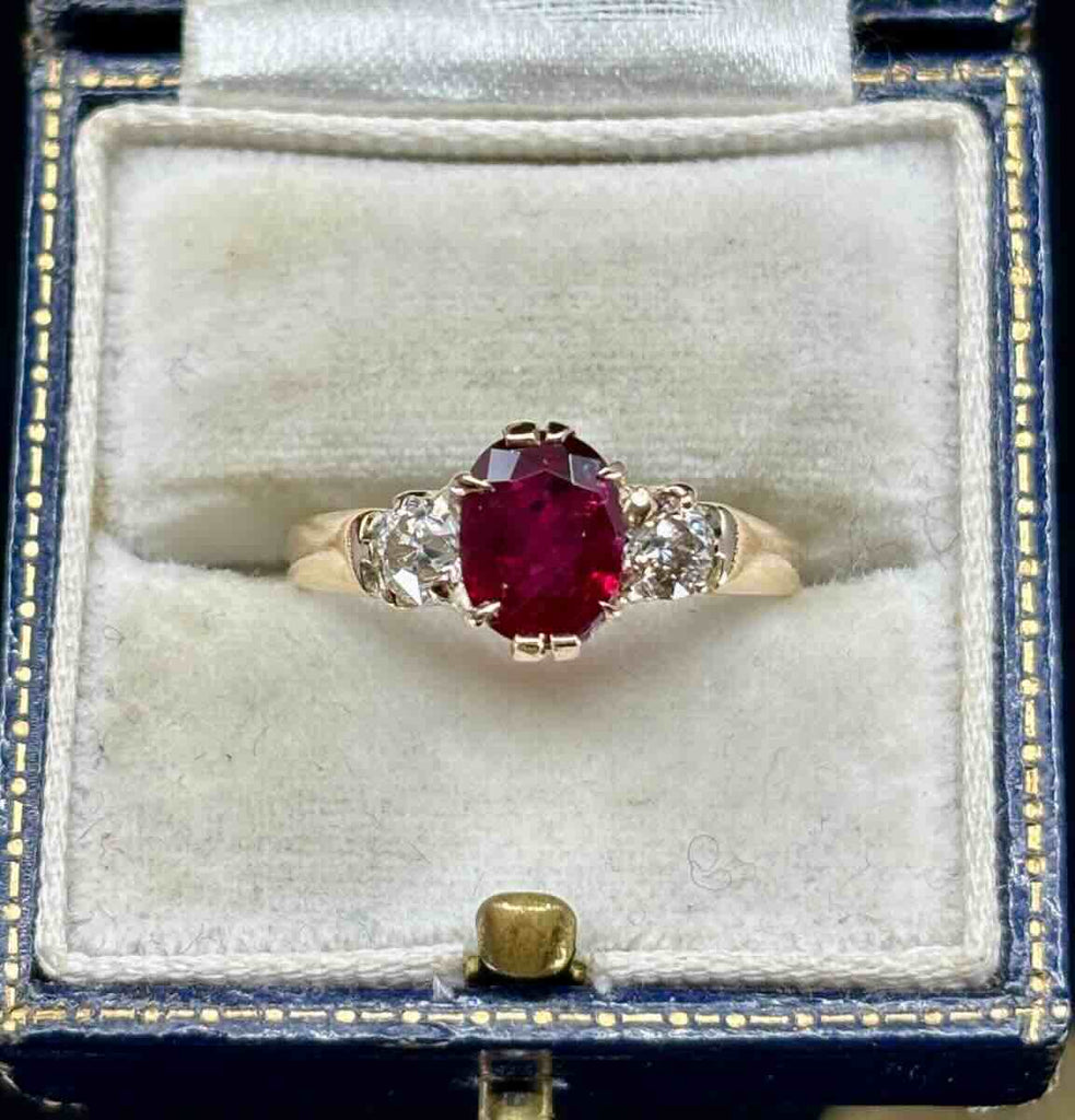 Antique Edwardian 1905 three‑stone ring with 2.53ct oval ruby and two old‑European cut diamonds (0.46ct) in 9ct yellow gold — claw set, vintage engagement ring.