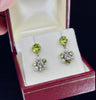 Close-up view of antique Edwardian earrings with old mine cut diamonds, vibrant peridots, and lustrous pearls, highlighting intricate craftsmanship and design.