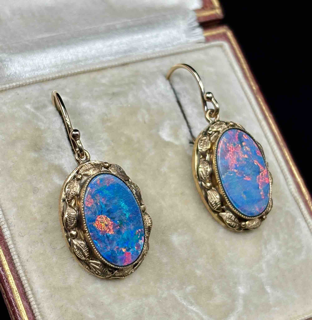 Antique gold opal earrings shown at an angle highlighting the repoussé leaf frame