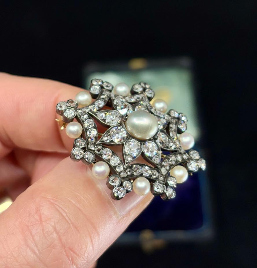 Close-up detail of the central ovoid pearl and diamond settings in a Victorian brooch.