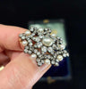 Close-up detail of the central ovoid pearl and diamond settings in a Victorian brooch.
