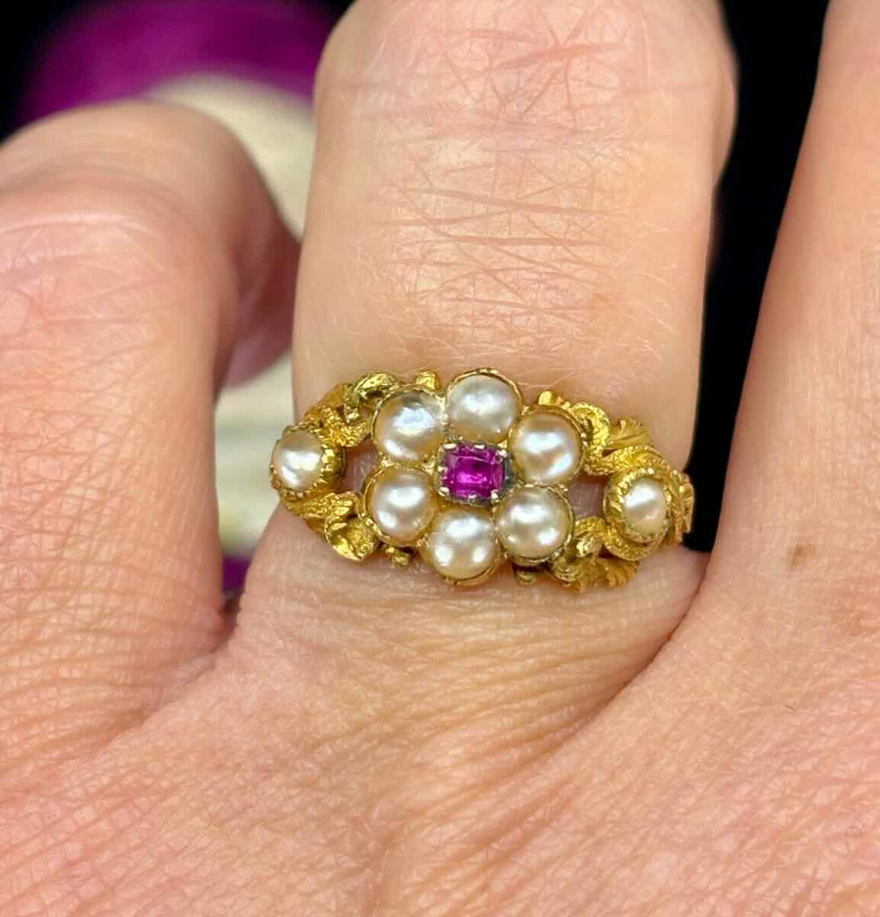 Antique ruby and pearl ring in 18ct gold in a floral posy cluster design, worn on the finger.