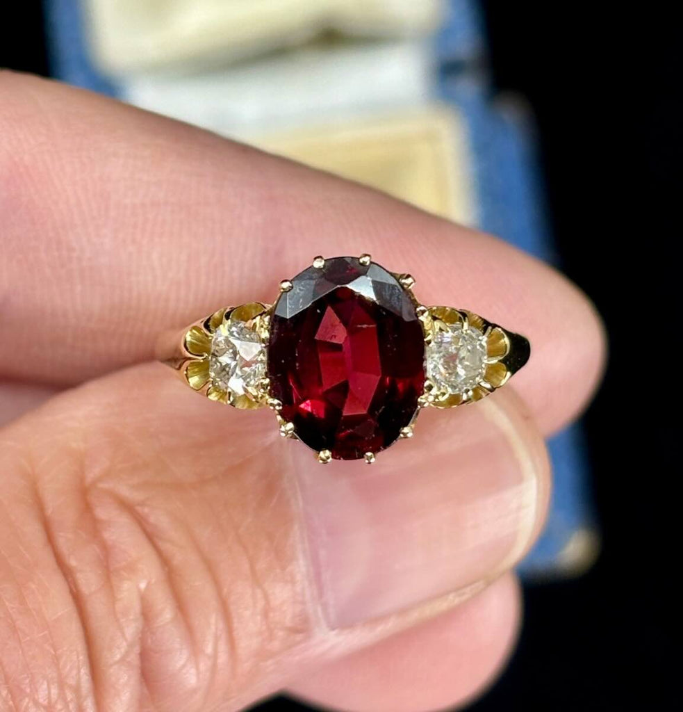 The antique Victorian 3ct oval garnet and diamond ring held up close