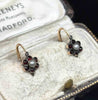 Antique Victorian daisy cluster earrings shown at an angle with garnet petals and pearl centres